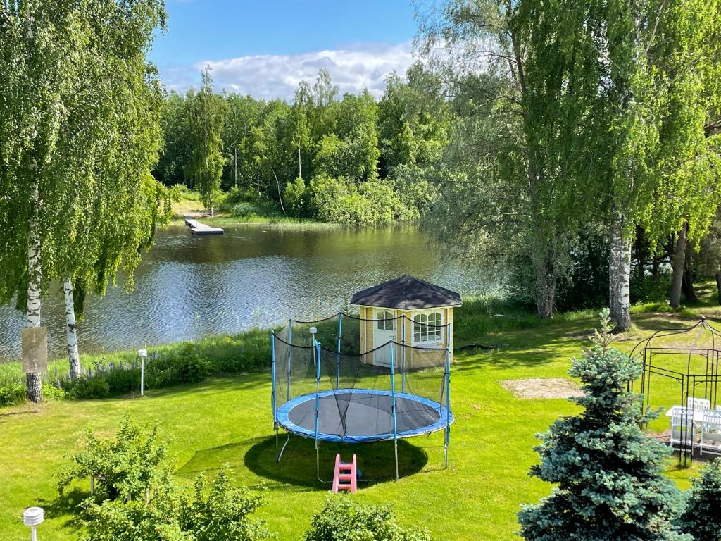 a playground in the grass next to a lake at Jokiranta in Kouvola