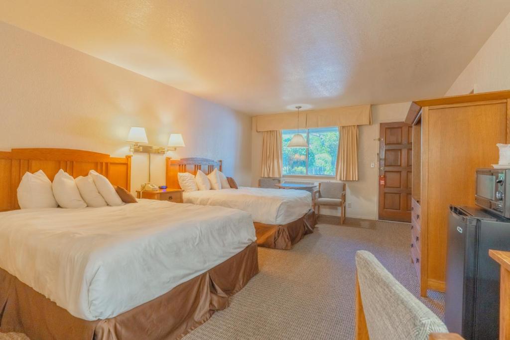 Cette chambre comprend deux lits et une télévision. dans l'établissement Mariposa Lodge, à Mariposa