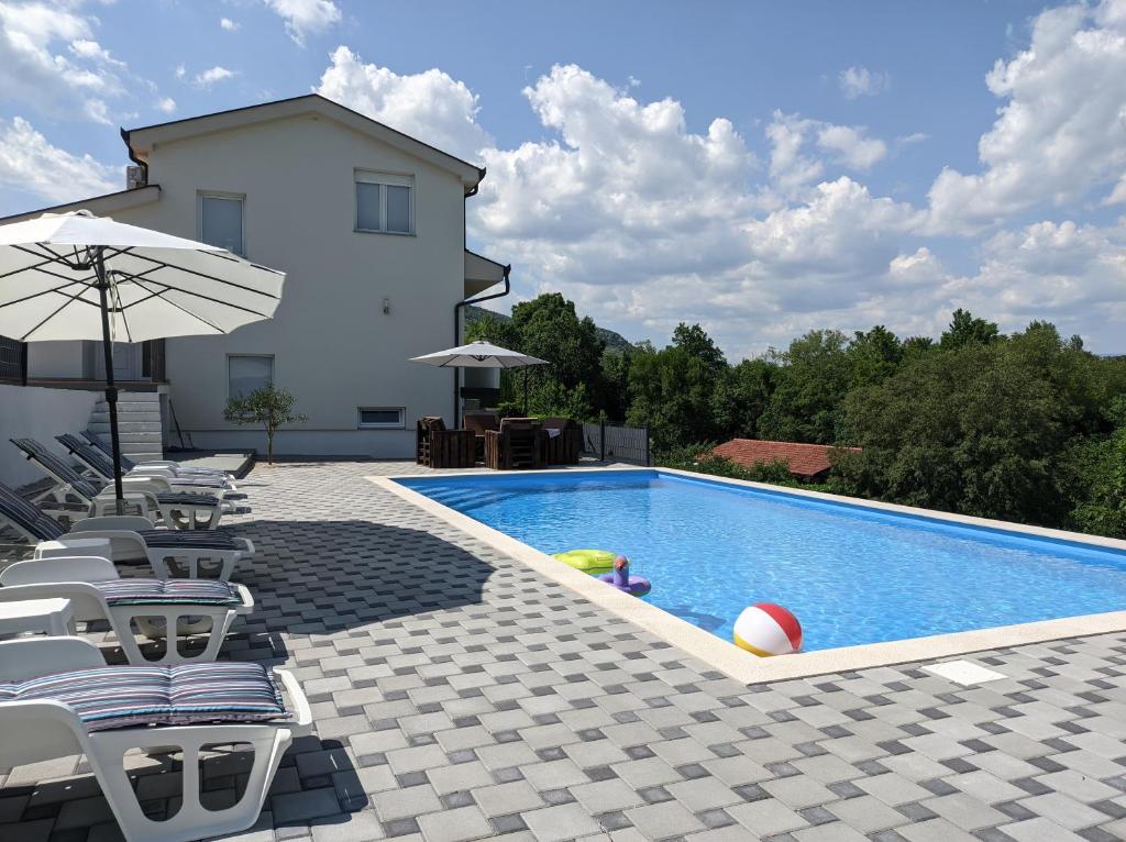 einen Pool mit Stühlen und einem Sonnenschirm neben einem Haus in der Unterkunft Villa Longina in Ljubuški