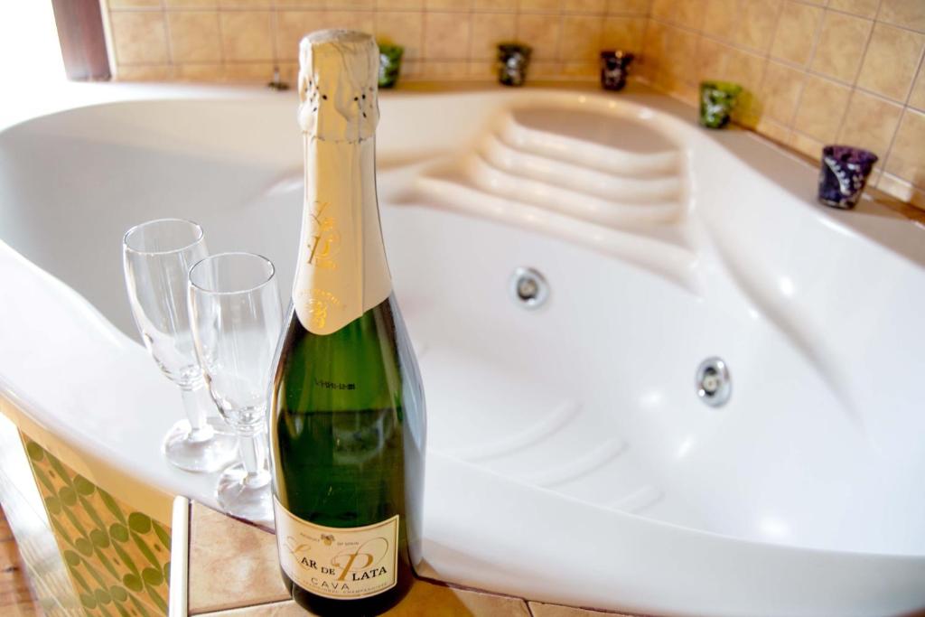 eine Flasche Champagner in einer Badewanne mit zwei Gläsern in der Unterkunft Suite Love in Gilgarcía