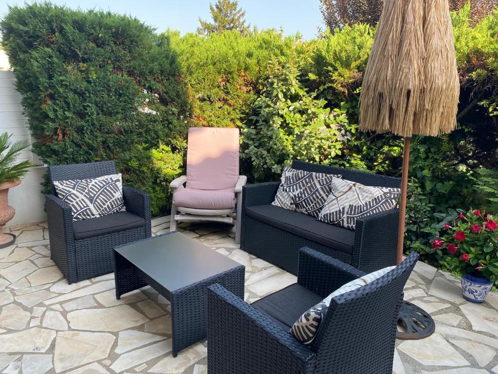 eine Terrasse mit Stühlen, einem Tisch und einem Sonnenschirm in der Unterkunft maison Basque Maïana in Anglet