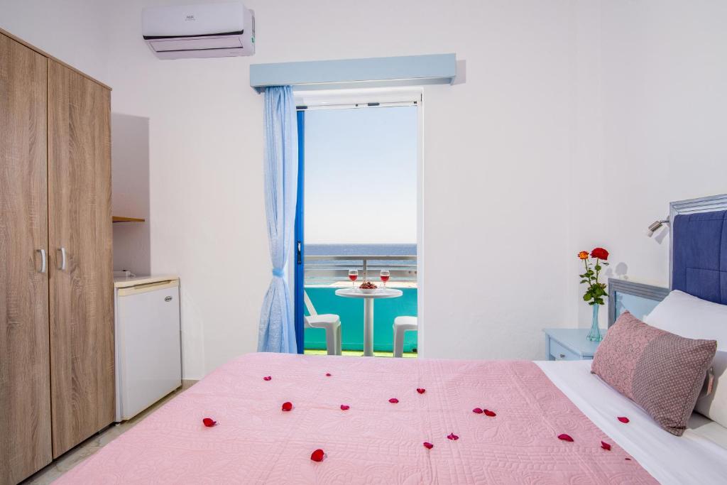 a bedroom with a pink bed with roses on it at Klima Rooms in Palaiochóra