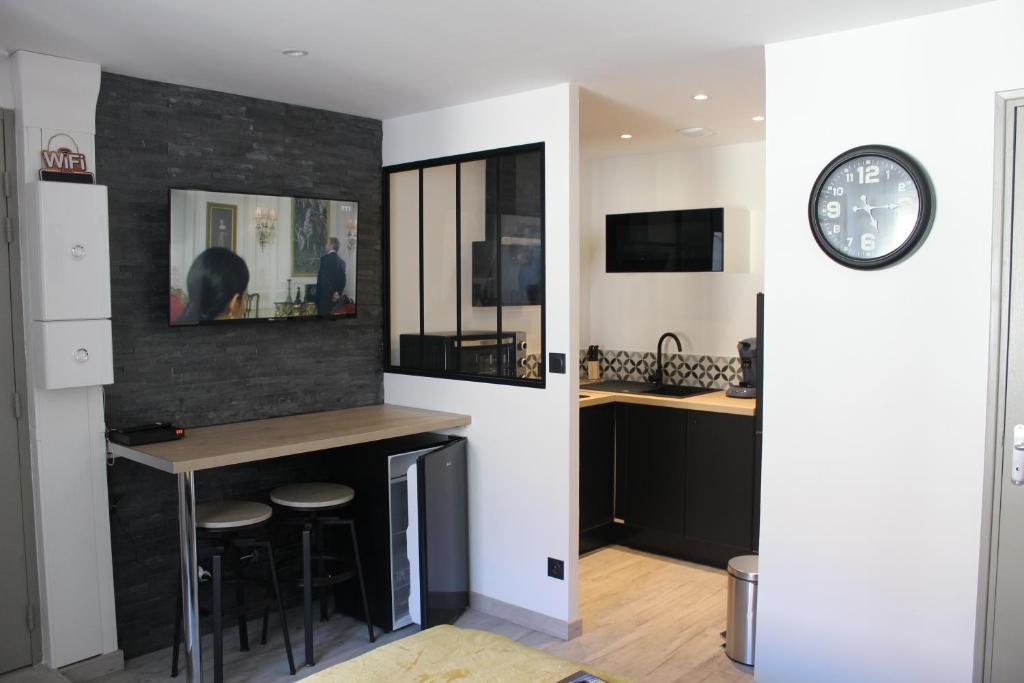 a kitchen with a bar and a clock on the wall at Studio Les pieds dans l'eau in Dieppe