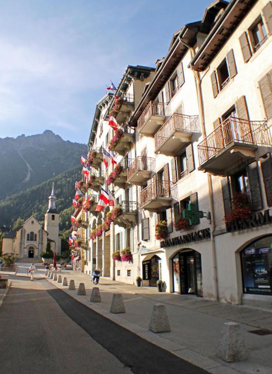 un bâtiment avec des drapeaux sur le côté d'une rue dans l'établissement Apartment Relais de Poste Centre Chamonix Mont Blanc, à Chamonix-Mont-Blanc