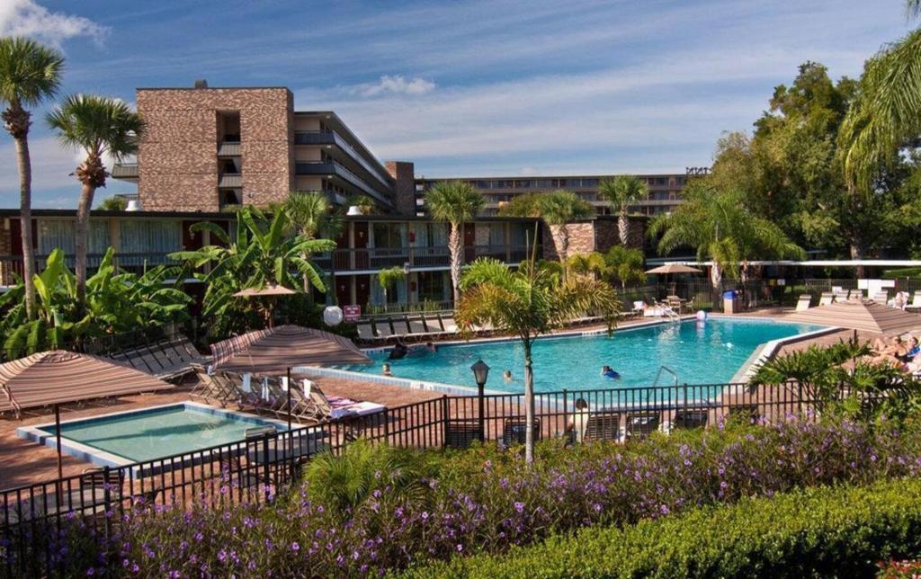 a pool at a resort with palm trees and a building at Rosen Inn International Near The Parks in Orlando
