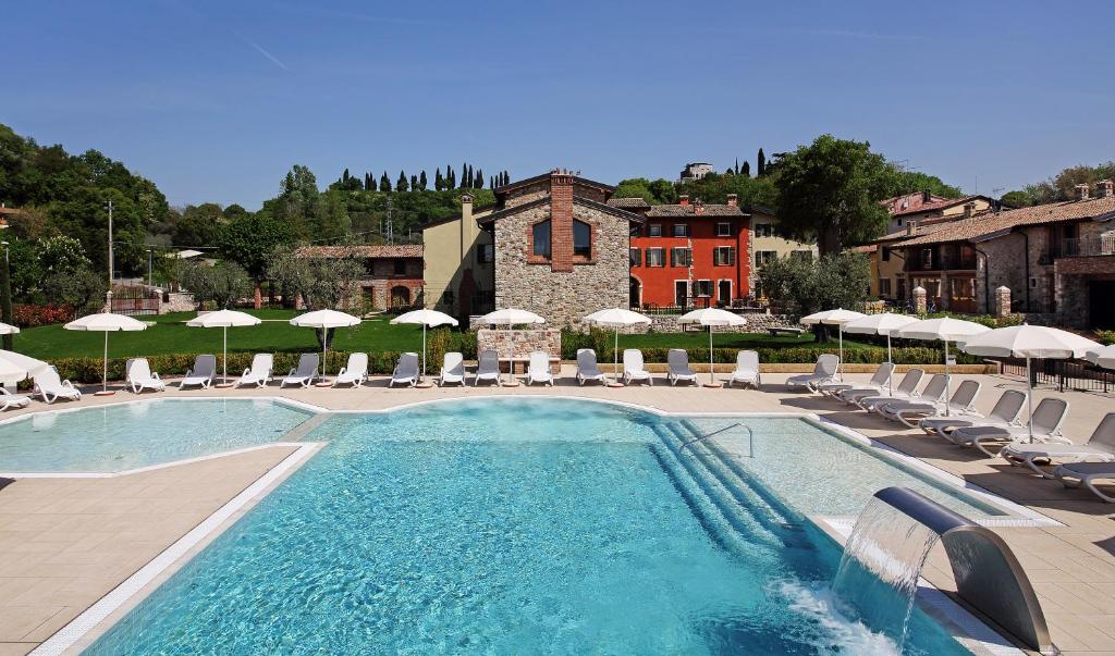 a swimming pool with lounge chairs and umbrellas at Residence Borgo Mondragon in Lazise