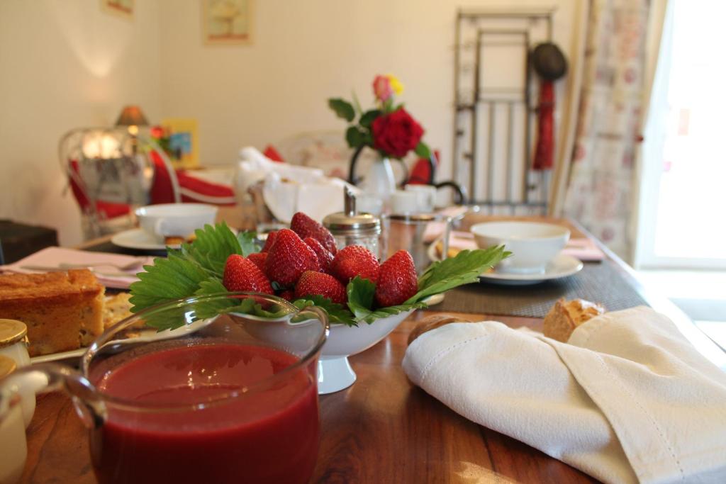 una mesa con un tazón de fresas y una taza de té en La Ferme du bois Paris, en Ermenonville-la-Petite