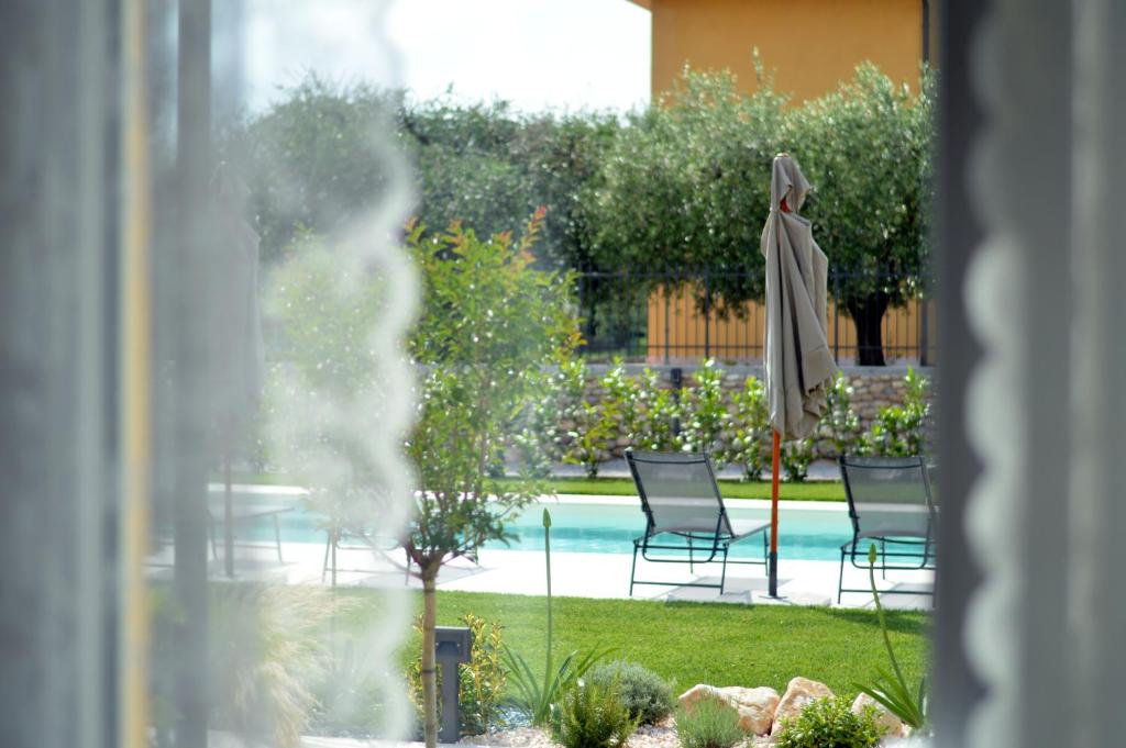 uitzicht op een zwembad met stoelen en een parasol bij Agriturismo Pepe Rosa in Rivoli Veronese