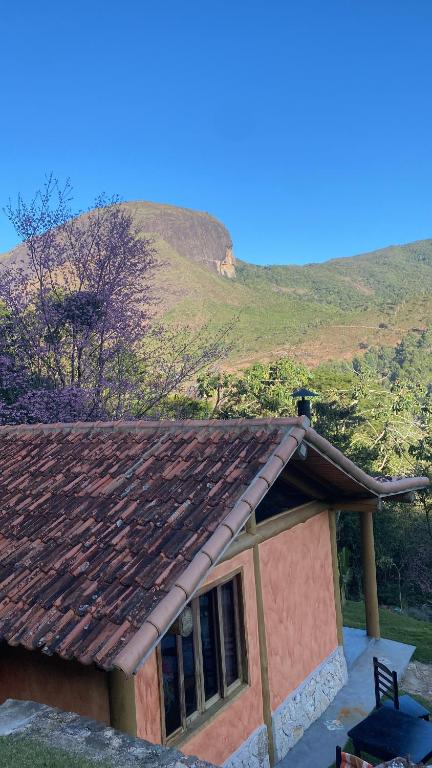 una pequeña casa con una montaña en el fondo en Recanto dia dourado, en Petrópolis