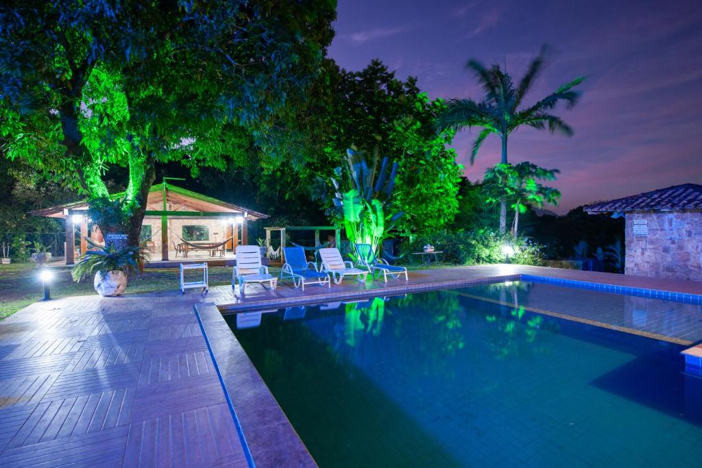 a swimming pool with chairs and a house at night at Sitio Toca do Leao in Guarapari