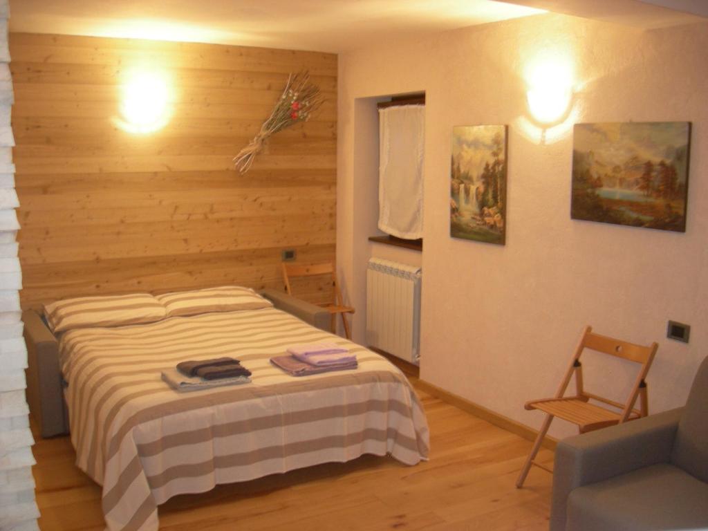 1 dormitorio con 1 cama y 1 silla en Zimmer Arianna, en Alpe Strencia