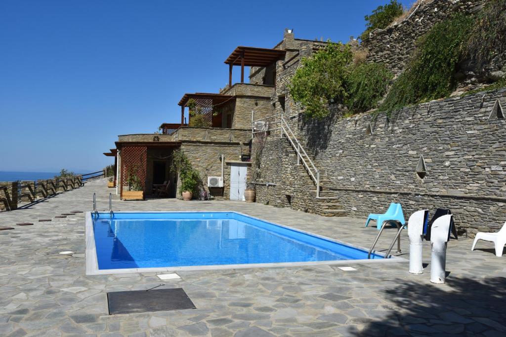 a swimming pool in front of a stone building at Andros Escape Condos in Andros