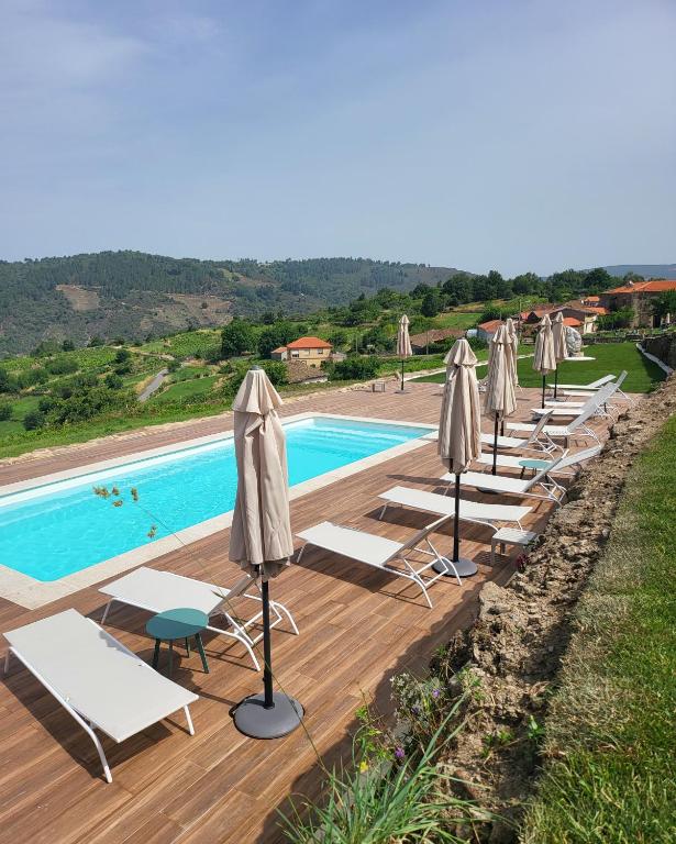 a row of chairs and umbrellas next to a pool at Miradores do Sil Hotel Apartamento in Cristosende