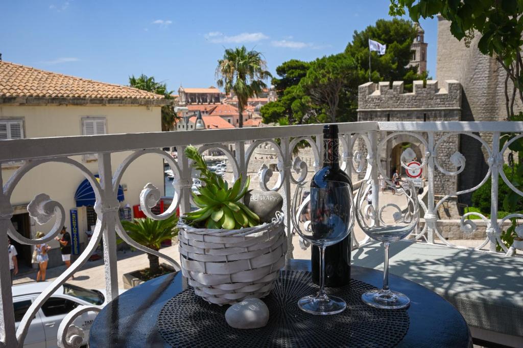 einen Tisch mit einer Flasche und zwei Gläsern auf dem Balkon in der Unterkunft Guesthouse Nada in Dubrovnik