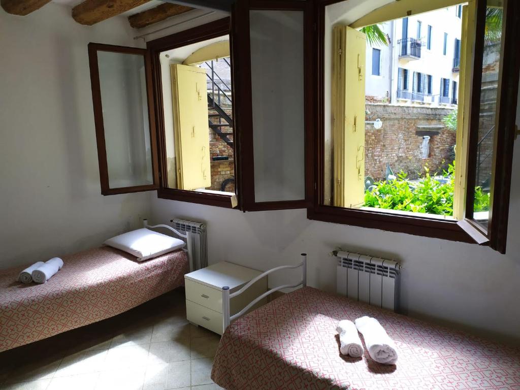 2 Betten in einem Zimmer mit 2 Fenstern in der Unterkunft CANAL VIEW in Venedig