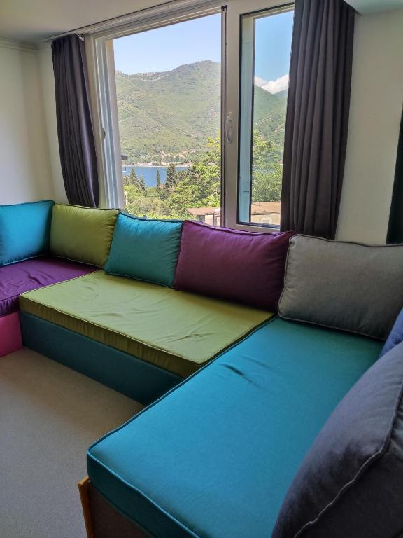 a room with a couch with a large window at Montenegro Colors Kamenari in Kamenari