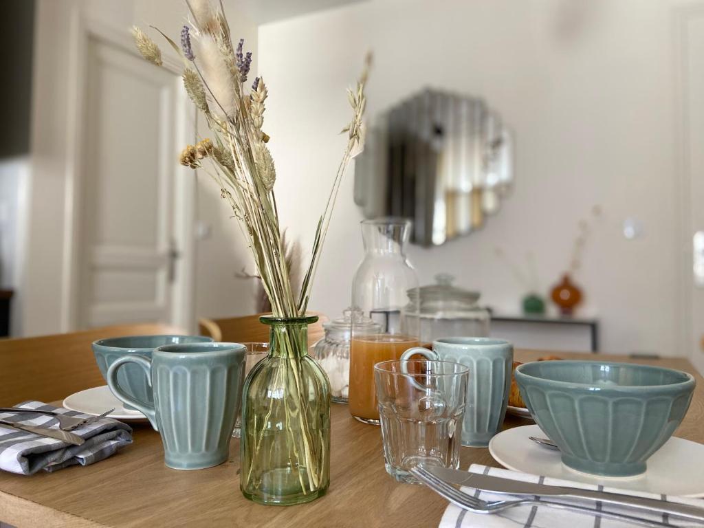 a table with blue bowls and a vase with flowers in it at Le KEMPER - Cœur de ville in Quimper