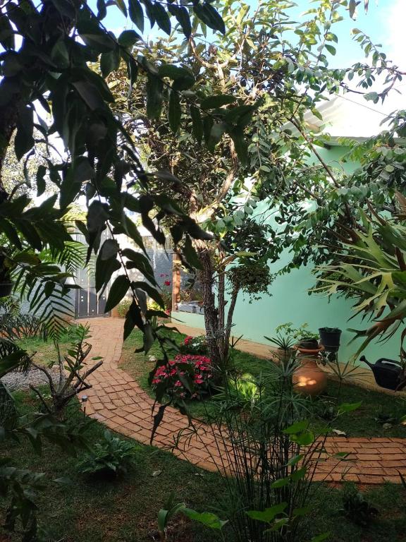 a garden with a brick walkway with trees and flowers at Flores do Cerrado in Alto Paraíso de Goiás