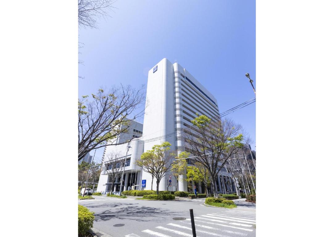 a tall white building with a street in front of it at Ariston Hotel Kobe in Kobe