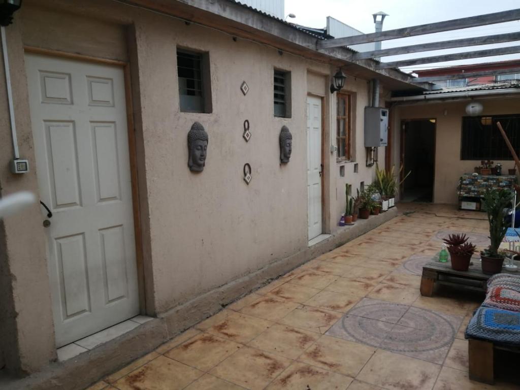 an empty courtyard with a white door and some plants at Hostal CacTus in Coquimbo