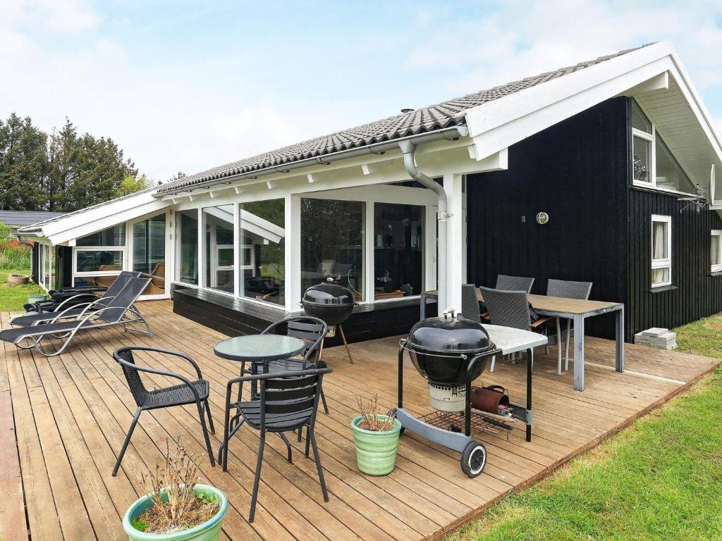 una terraza con parrilla, mesas y sillas en 10 person holiday home in Hj rring, en Lønstrup