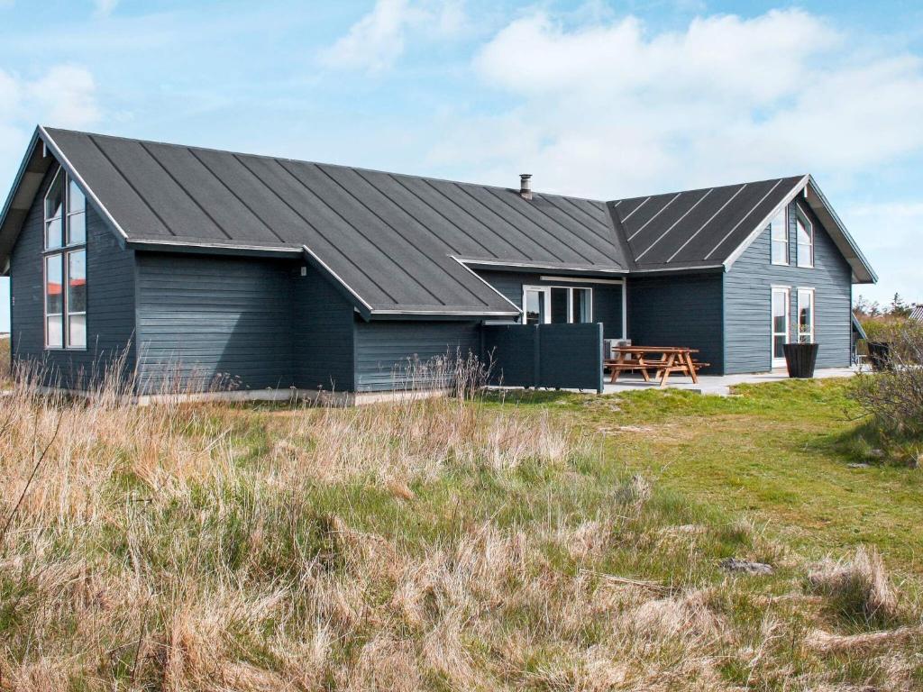 a house with a black roof on a grass field at 18 person holiday home in Harbo re in Harboør