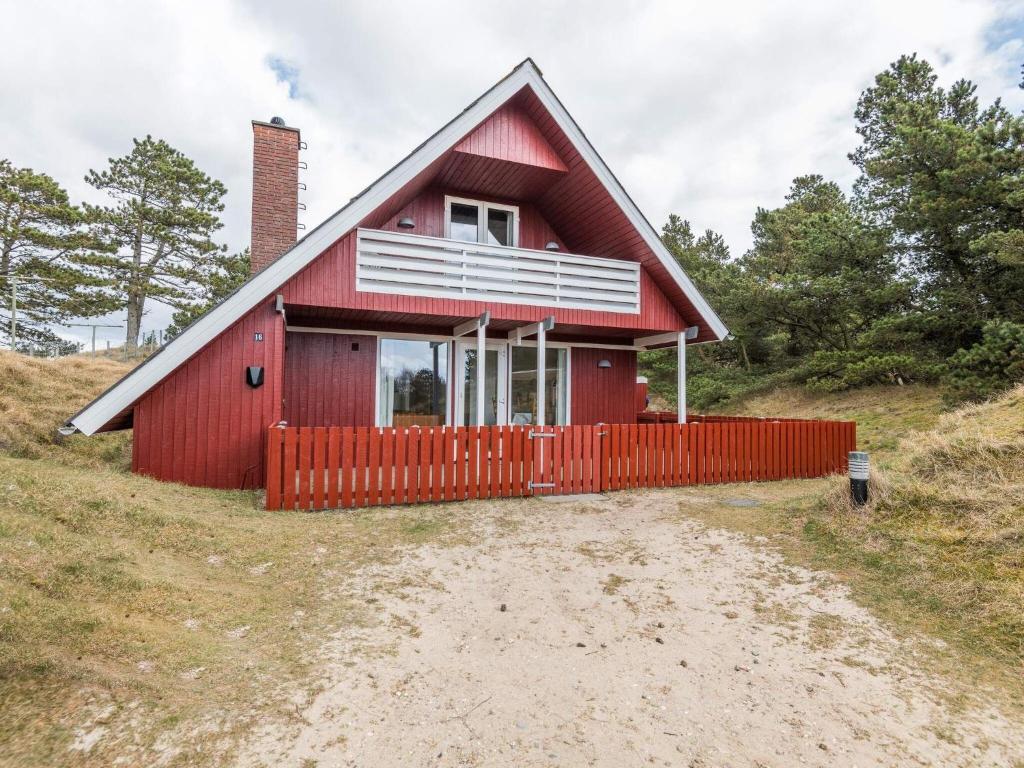 une maison rouge avec une clôture rouge sur une colline dans l'établissement Holiday home Fanø XLIV, à Fanø