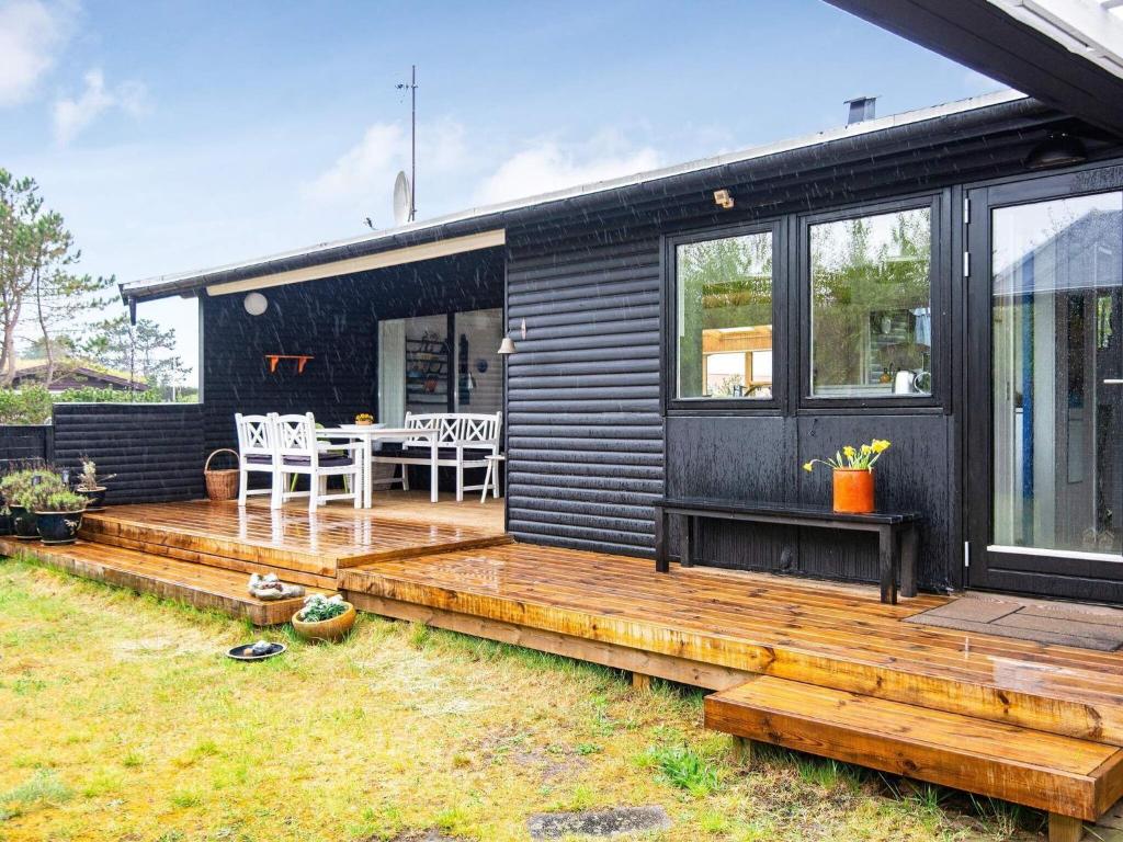 a black house with a wooden deck and a table at 6 person holiday home in Glesborg in Glesborg