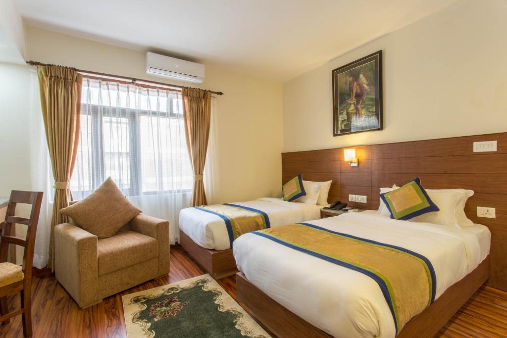um quarto de hotel com duas camas e uma cadeira em Oasis Kathmandu Hotel em Catmandu