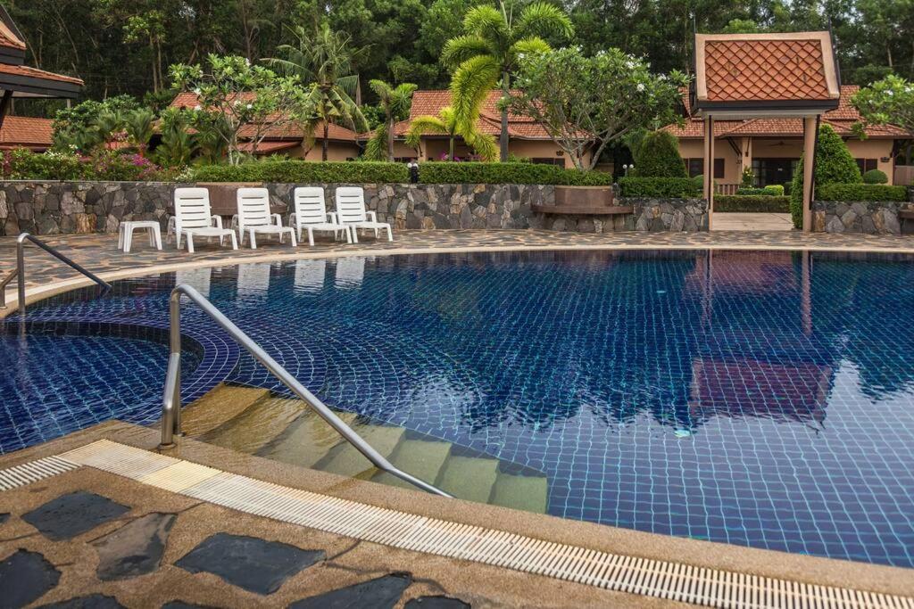 a swimming pool with lounge chairs and a resort at Family-friendly house, a few steps from the pool and close to the ocean. in Mae Pim