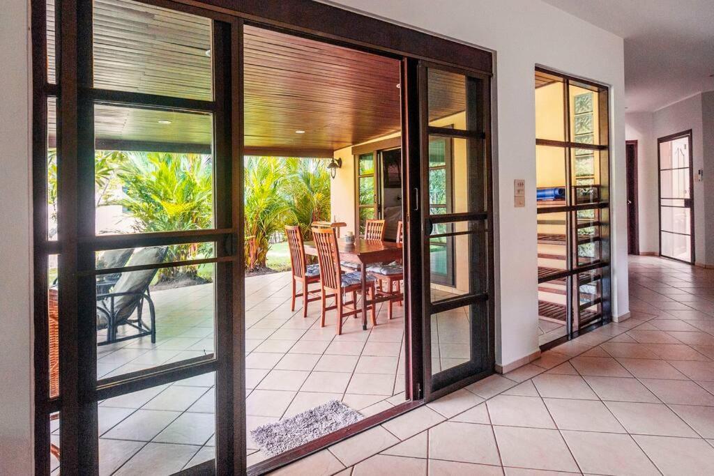a living room with sliding glass doors and a dining room at Family-friendly house, a few steps from the pool and close to the ocean. in Mae Pim