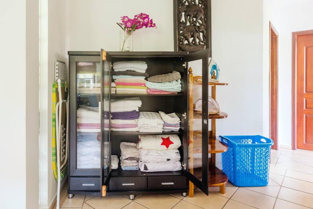 a closet with a glass cabinet filled with towels at Family-friendly house, a few steps from the pool and close to the ocean. in Mae Pim
