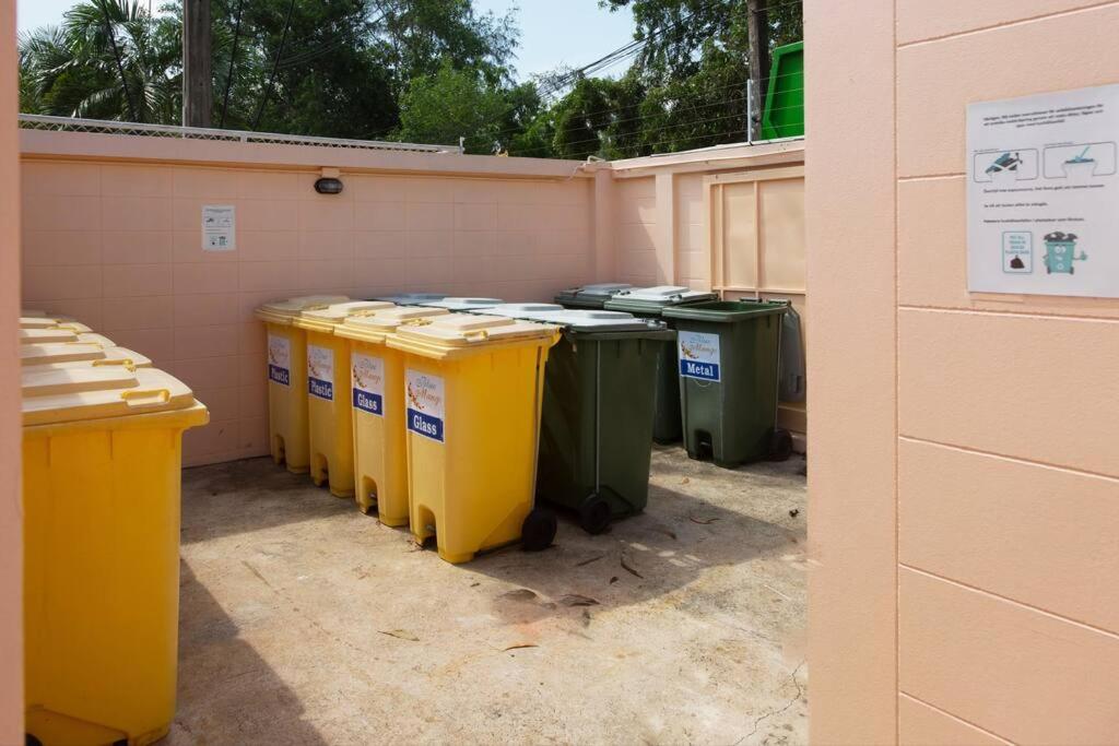 a row of trash cans sitting next to a wall at Family-friendly house, a few steps from the pool and close to the ocean. in Mae Pim