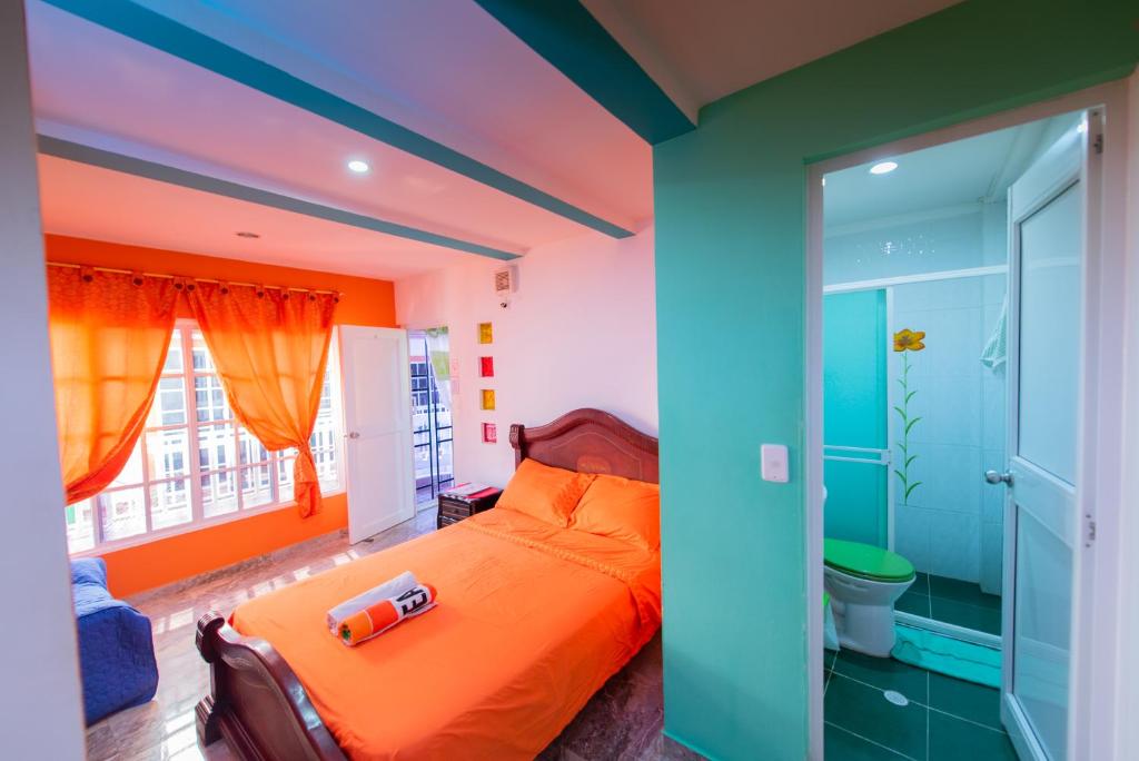 1 dormitorio con cama de color naranja y baño en Apartamentos Turísticos El Conquistador, en San Andrés