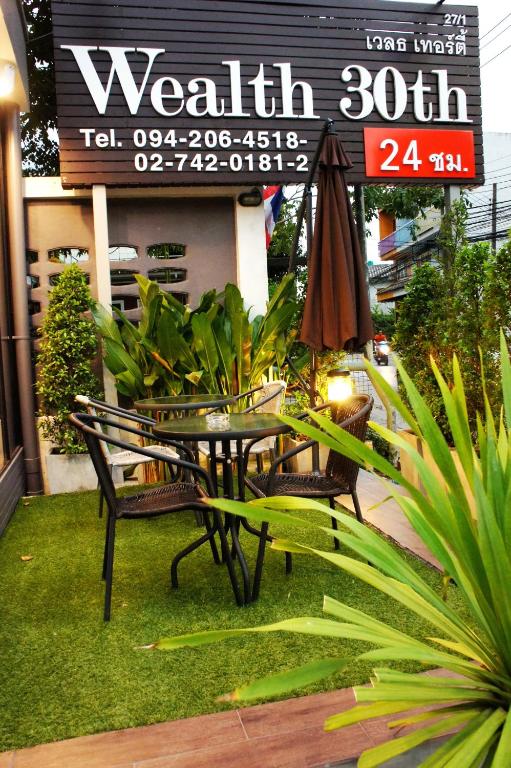 A small outdoor dining area beside the Wealth 30th entrance sign.