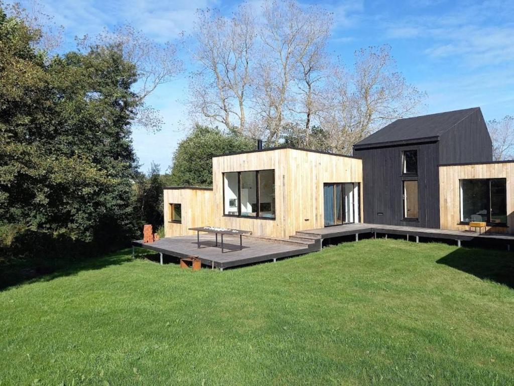 une maison avec un toit noir sur une pelouse dans l'établissement Villa neuve en bois avec WIFI et jardin, à proximité de la plage de Trestraou, Perros-Guirec - FR-1-368-353, à Perros-Guirec