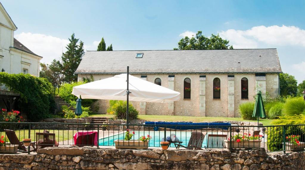 a house with a pool and an umbrella at Domaine de la Courbe in Le Lude