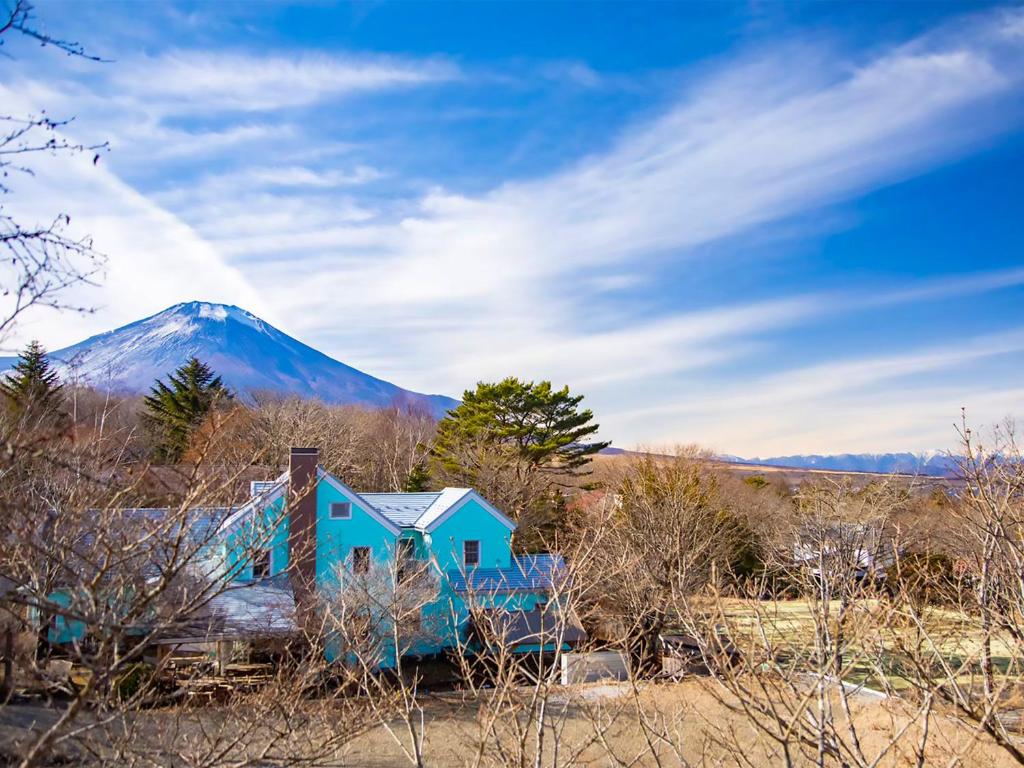 una casa en un campo con una montaña en el fondo en Human resort, en Yamanakako