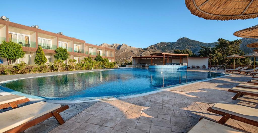 a large swimming pool with chairs and a building at Anavadia Hotel-All Inclusive in Kolymbia