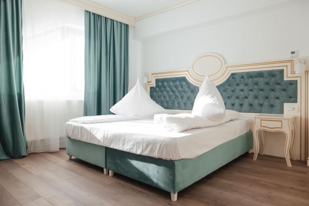 a bedroom with a large bed with a blue headboard at Hotel Miruna in Sâmbăta de Sus