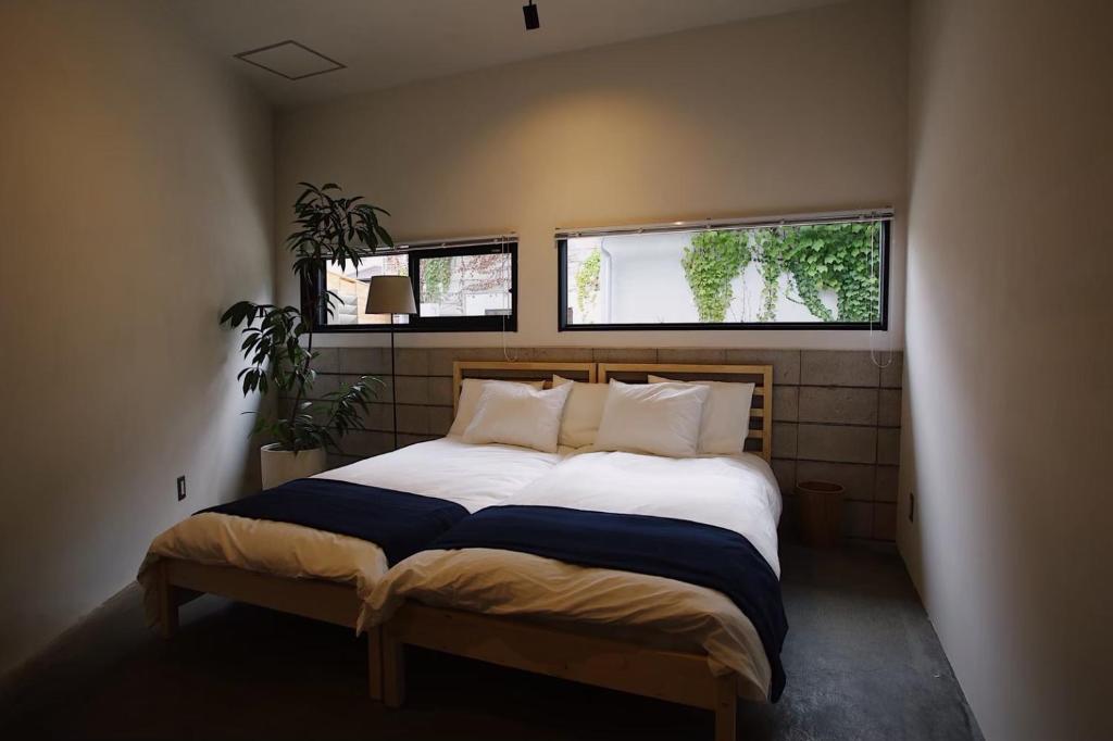 um quarto com uma cama grande e 2 janelas em hostel mog em Ueda