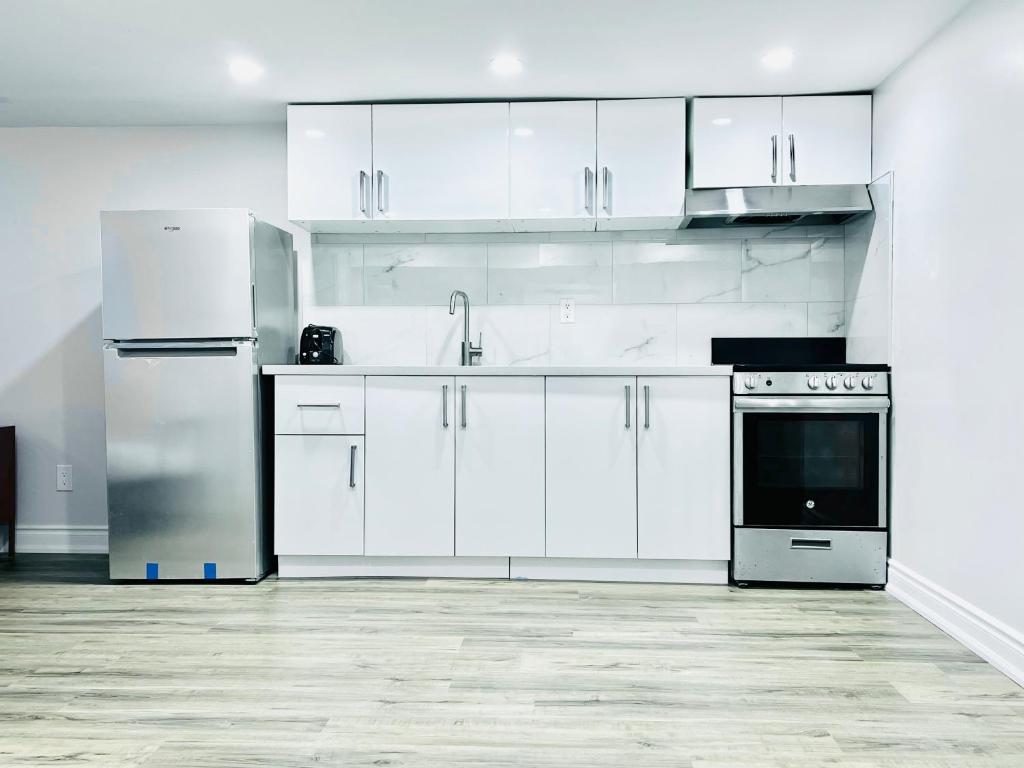 una cocina blanca con armarios y electrodomésticos blancos en Kensington Market House, en Toronto