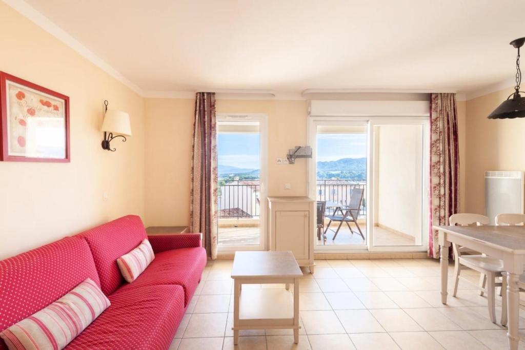 - un salon avec un canapé rouge et une table dans l'établissement Les Coteaux de Pont Royal en Provence - maeva Home - Appartement 2 Pièces 4 16, à Mallemort