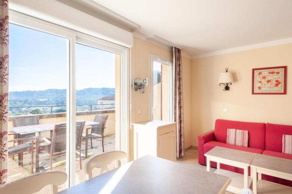 ein Wohnzimmer mit einem roten Sofa und einem Balkon in der Unterkunft Les Coteaux de Pont Royal en Provence - maeva Home - Appartement 2 Pièces 4 22 in Mallemort
