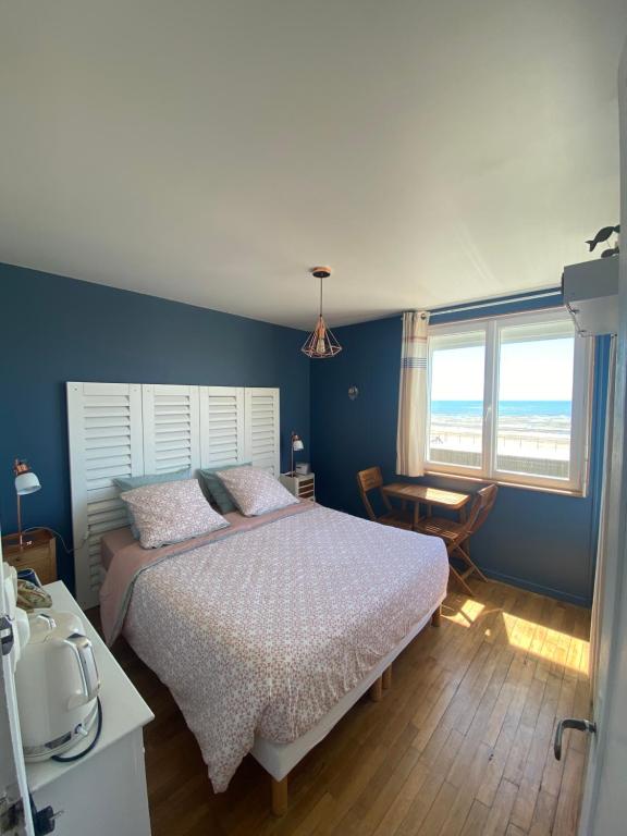 - une chambre avec un lit, une table et une fenêtre dans l'établissement La Villa plein vent "Lumière du Cap" vue mer, à Barneville-Carteret