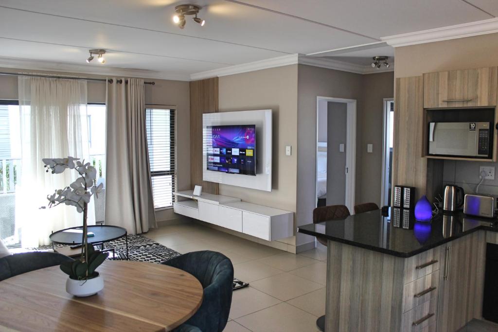 uma grande sala de estar com uma mesa e uma televisão em White Orchid Luxury Apartment em Chartwell