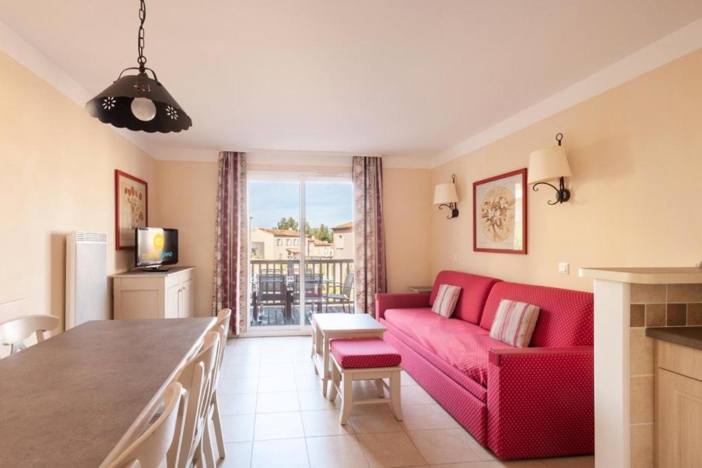 sala de estar con sofá rojo y mesa en Les Coteaux de Pont Royal en Provence - maeva Home - Maison 3 Pièces 6 Perso 77, en Mallemort