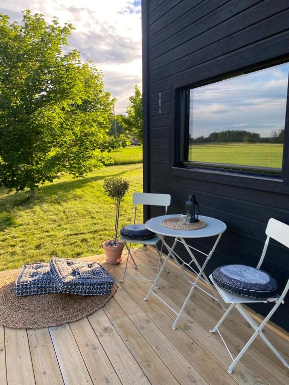 een patio met 2 stoelen, een tafel en een raam bij Field View Cabin in Örebro