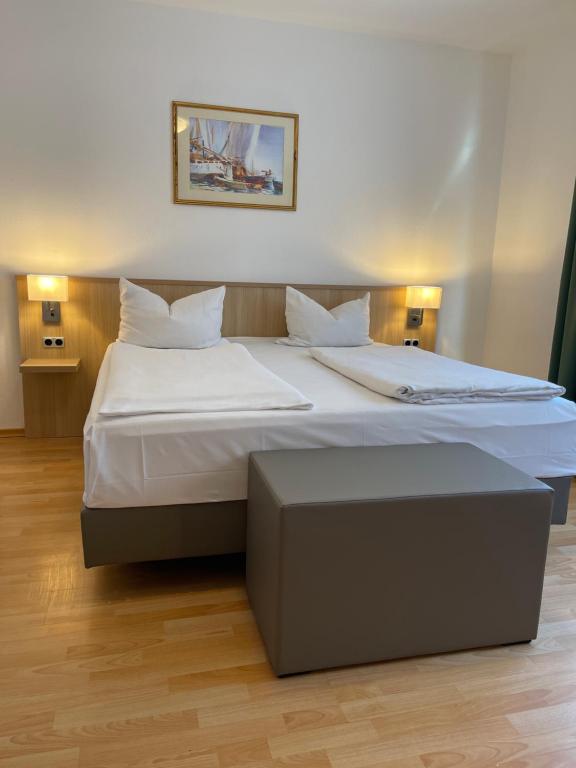 um quarto com uma cama grande com lençóis brancos e almofadas em Hafner Hotel- Apartment em Stuttgart