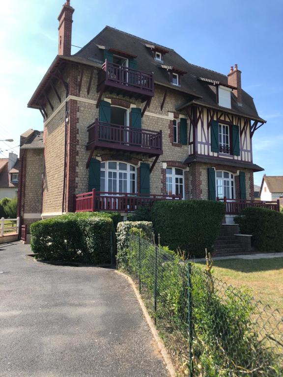 een groot bakstenen huis met een hek ervoor bij L oceanide in Bénerville-sur-Mer